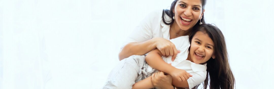 Hispanic woman holding little girl smiling
